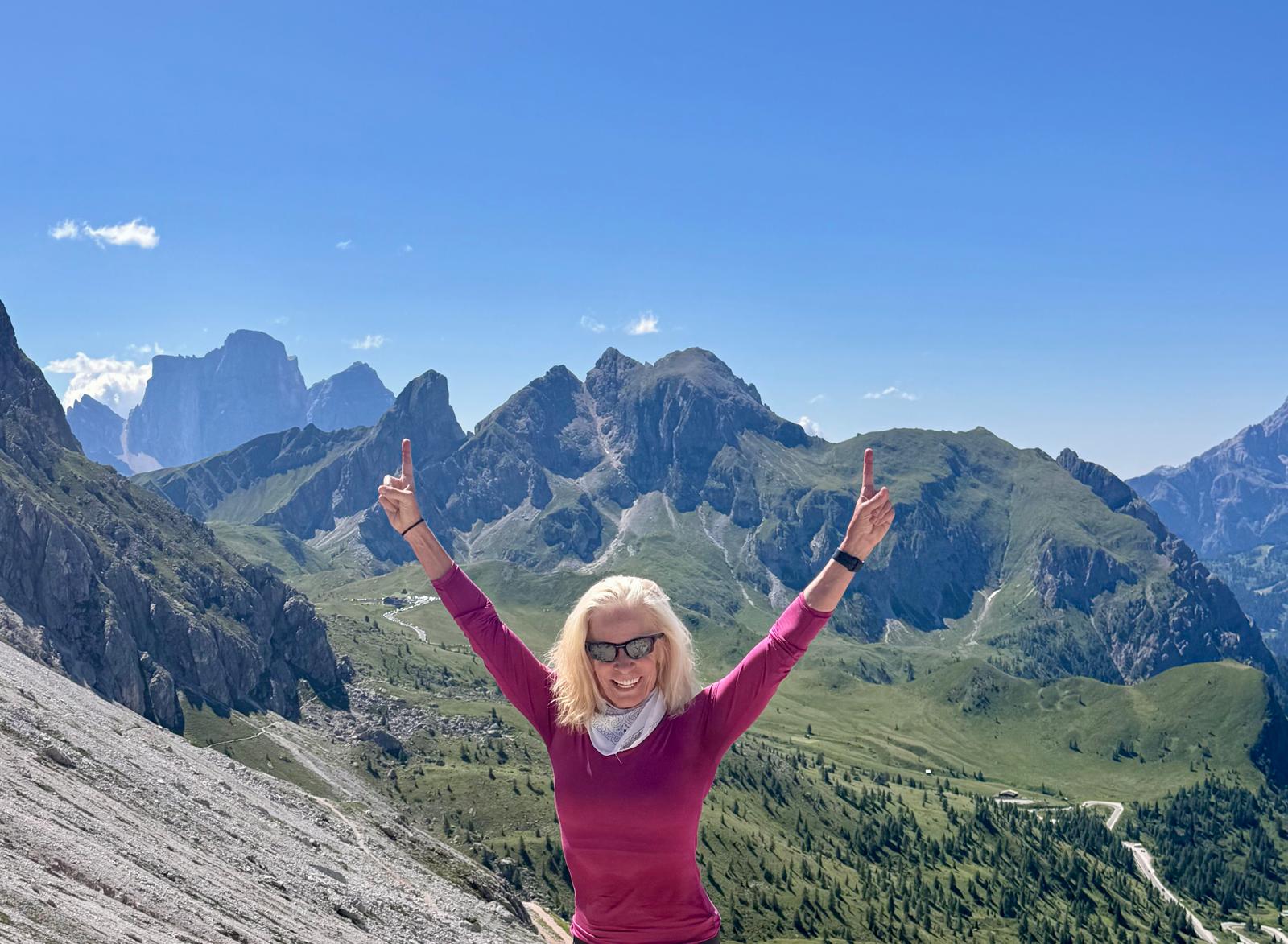 Carol celebrating at the top of a mountain pass in the Dolomites