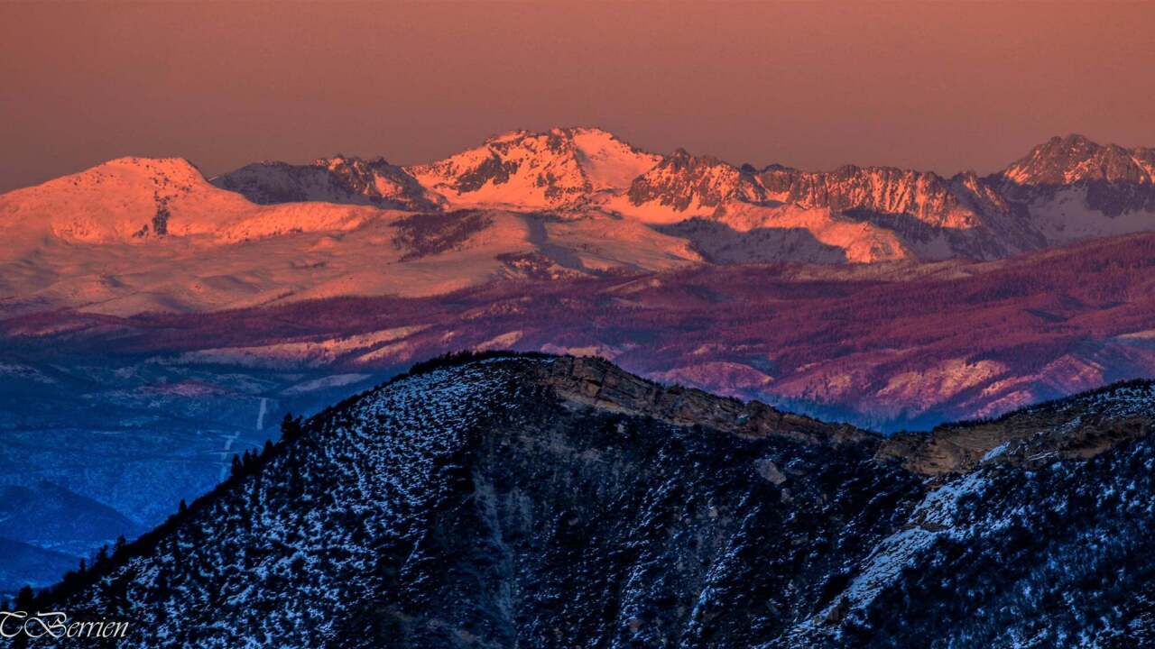 Snow-capped peaks glowing under a dramatic sunset alpenglow